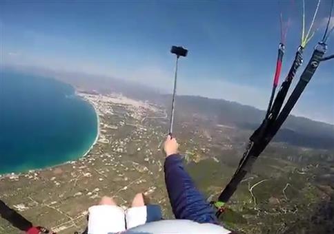 Er hantiert mit dem Selfiestick beim Paragliden