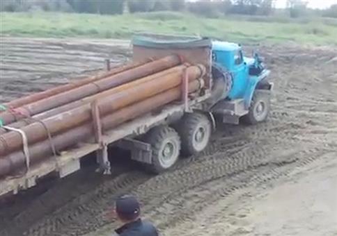 LKW mit langen Rohren fährt auf eine Fähre