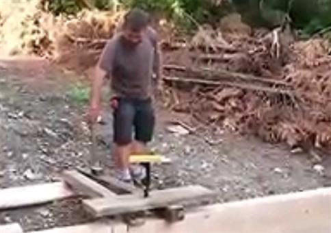 Flasche Bier mit einem Hammer in ein Brett schlagen