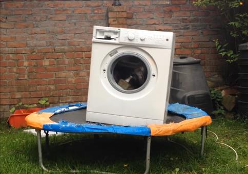Waschmaschine mit Ziegelsteinen beladen auf einem Trampolin