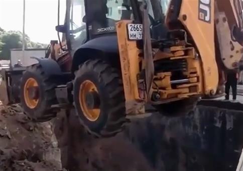 Kran lädt Radlader in Grube ab