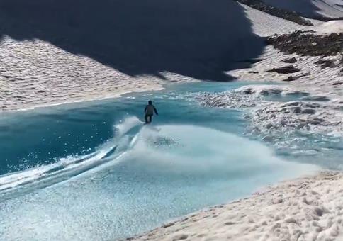 Mit dem Snowboard über einen Gebirgssee